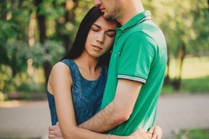 Young beautiful woman and young man embracing each other in summer park, tender scene. Couple in love